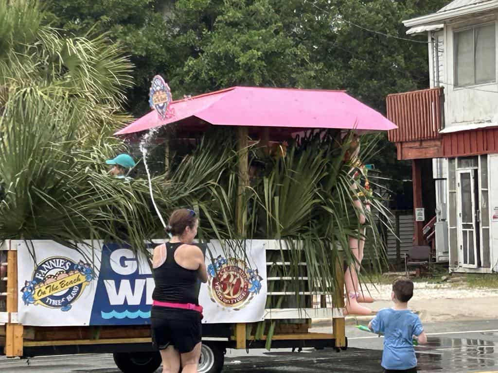 Mom and son spraying water guns at a float at the Tybee Island Beach Bum Parade
