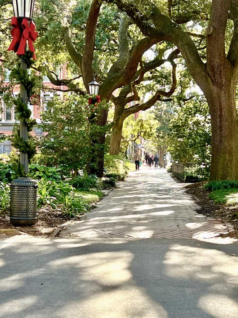 view down Savannah sidewalk with Christmas bow on lamppost.