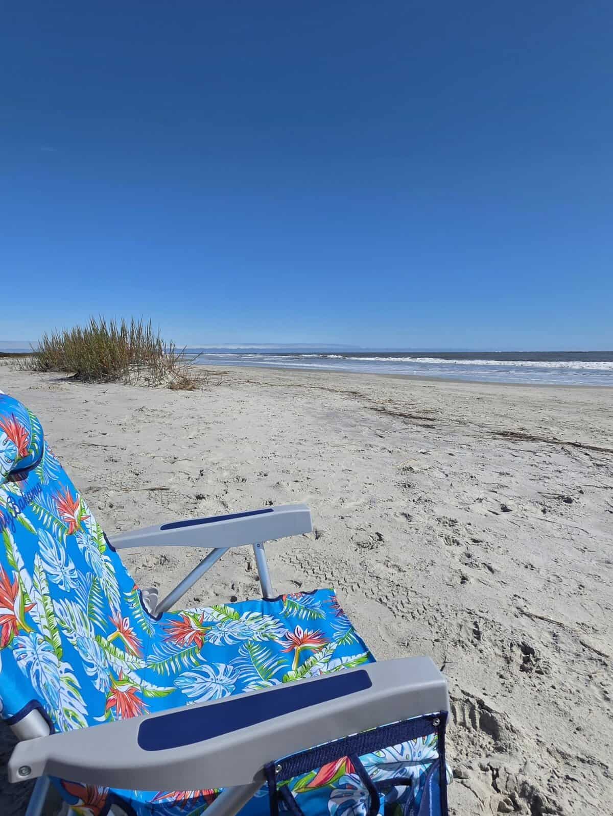 Myrtle Street Beach on St. Simons Island with a blue beach chair in the foreground. 