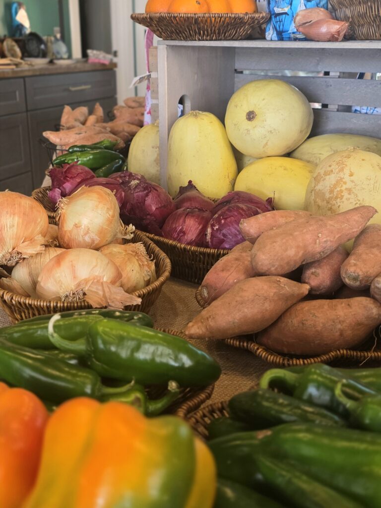Peppers, cucumbers, onions, sweet potatoes, and spaghetti squash on a table. 