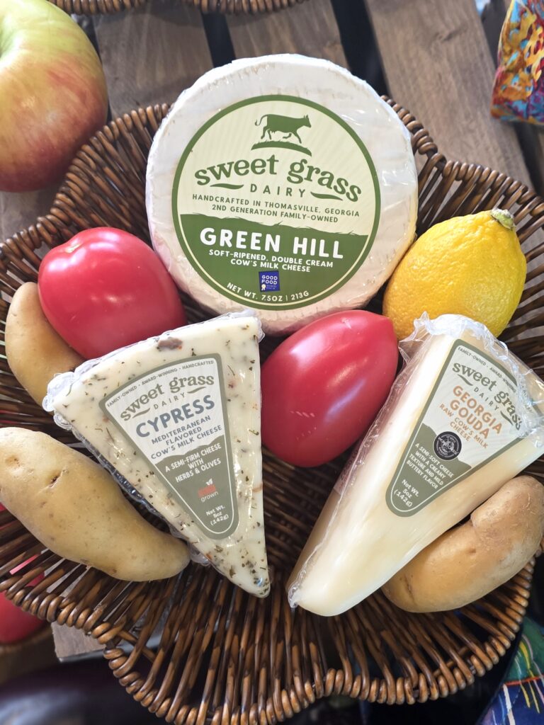 Sweet Grass Dairy cheeses in a wicker basket with produce from Farm 99.