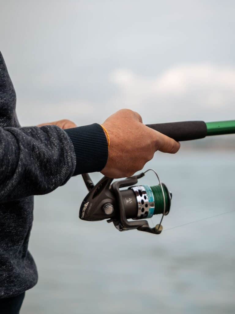close up of hands holding fishing reel.